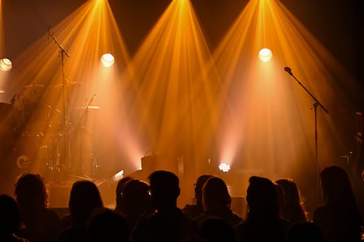 Bright lights illuminate the stage as musicians tune their instruments. A crowd gathers, eagerly anticipating a vibrant concert experience filled with energy and excitement.
