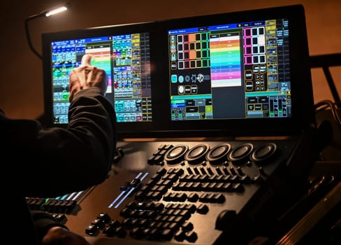 A skilled technician adjusts lighting settings on a digital control board, contributing to the electrifying ambiance of a live concert at a popular venue.