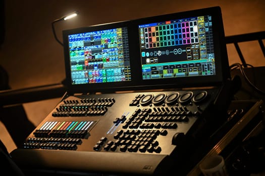 A skilled technician adjusts lighting settings on a digital control board, contributing to the electrifying ambiance of a live concert at a popular venue.