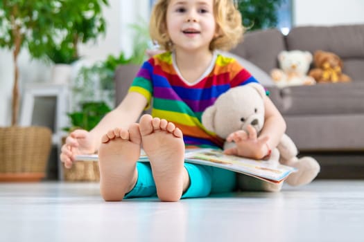 Child reading a book at home with a teddy bear at home. Selective focus. kid.