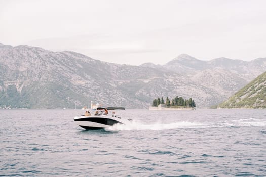 Motor yacht sails along the Bay of Kotor with the islands in the background. Montenegro. High quality photo
