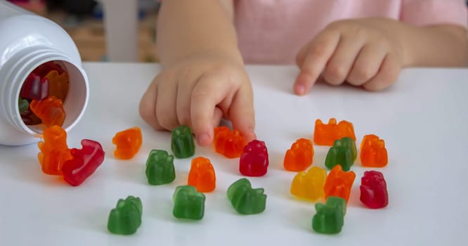 Little girl eating jelly candies or vitamins. child.