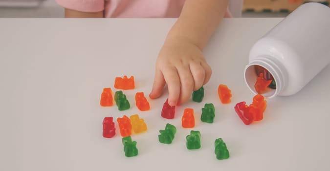 Little girl eating jelly candies or vitamins. child.