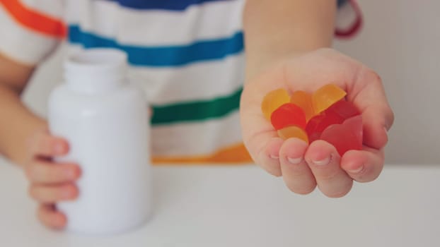 The boy eats jelly beans or takes vitamins.