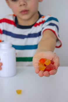 The boy eats jelly beans or takes vitamins.