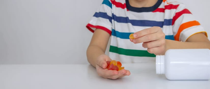The boy eats jelly beans or takes vitamins.