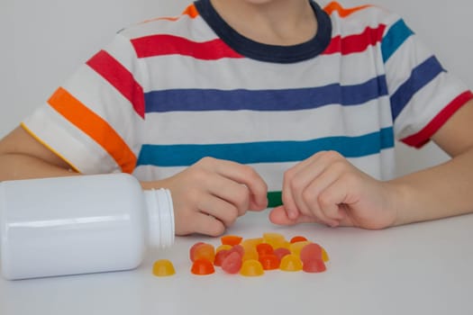 The boy eats jelly beans or takes vitamins.