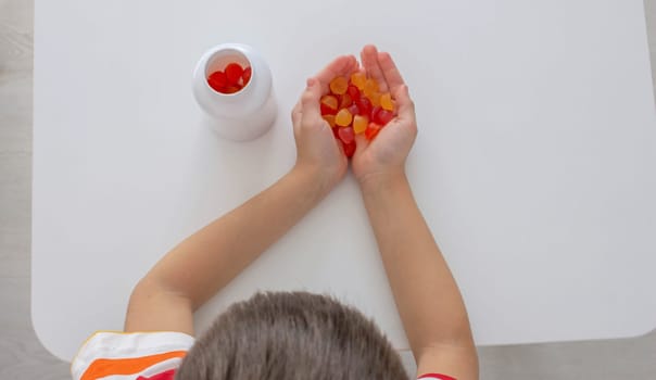 The boy eats jelly beans or takes vitamins.
