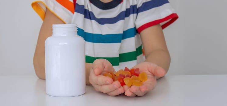 The boy eats jelly beans or takes vitamins.