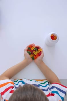 The boy eats jelly beans or takes vitamins.