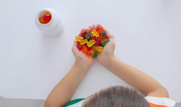 The boy eats jelly beans or takes vitamins.