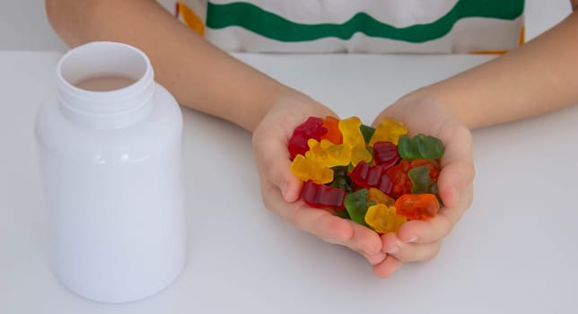 The boy eats jelly beans or takes vitamins.