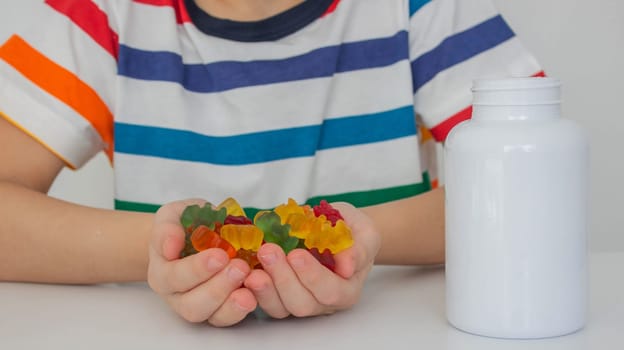 The boy eats jelly beans or takes vitamins.