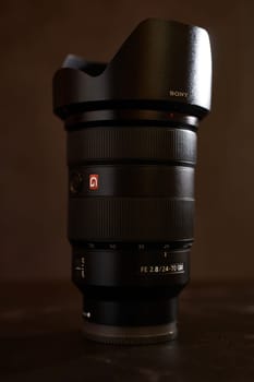 Replacement lens Sony FE 24-70mm for the camera stands on a black table. High quality photo