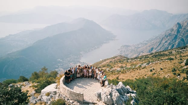 Group of tourists stands on an observation deck on a mountain above the Bay of Kotor. Montenegro. Drone. High quality photo