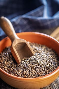 Milk thistle seeds in bowl on a wooden table.