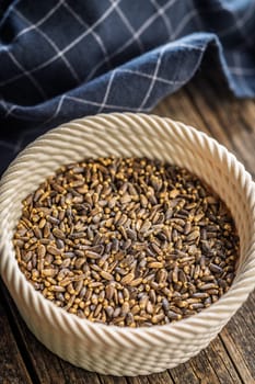 Milk thistle seeds in bowl on a wooden table.