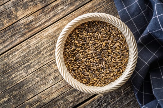 Milk thistle seeds in bowl on a wooden table. Top view.