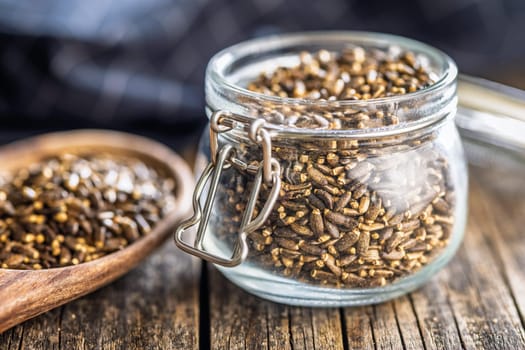 Milk thistle seeds in jar on a wooden table.
