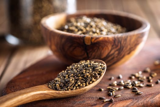 Milk thistle seeds on wooden spoon on a wooden table.