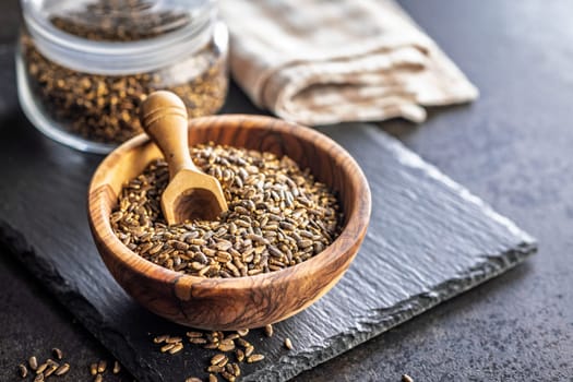 Milk thistle seeds in bowl on a black table.