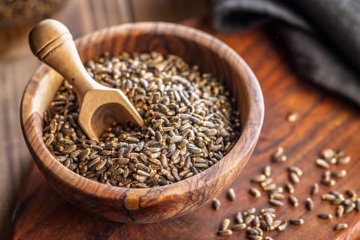 Milk thistle seeds in bowl on a wooden table.