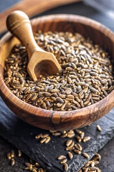 Milk thistle seeds in bowl on a black table.