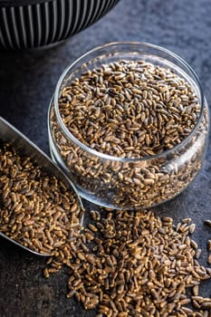 Milk thistle seeds in jar on a black table.