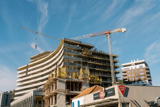 High tower cranes work at the construction site of a multi-storey building. High quality photo