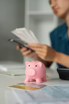 A focused individual assesses their savings strategy while gleefully interacting with a piggy bank, symbolizing financial health and smart choices.