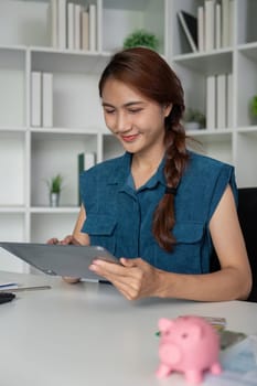 Sitting at her desk, a young woman engages with her tablet, reviewing financial insights and strategies for saving, demonstrating modern financial literacy.