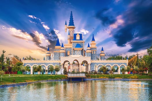 Beautiful fantastic fairy tale castle by lake at Magic City amusement Park in Tashkent in Uzbekistan at sunset