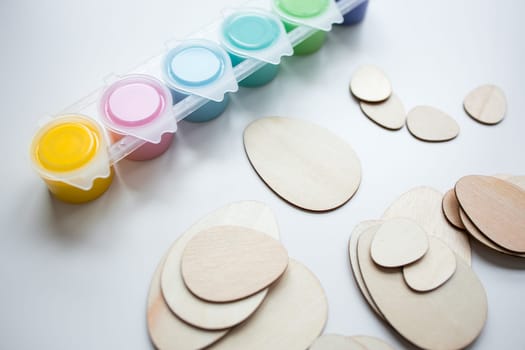 Assorted paints and wooden egg shapes for creative arts and crafts projects.