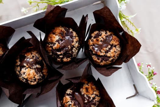 Delicious chocolate muffins with crumb topping in decorative brown wrappers.