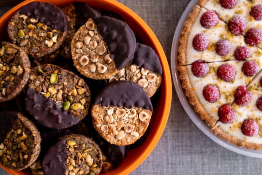 Assorted cookies with nuts and chocolate dipped sections next to raspberry tart.