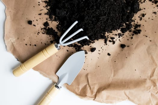 Gardening tools with soil on brown paper background.