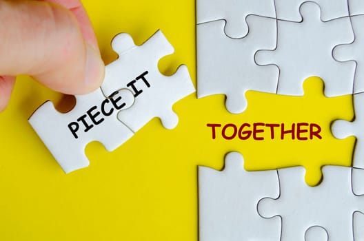 Piece it together text on missing jigsaw puzzle representing teamwork and unity. Teamwork concept.