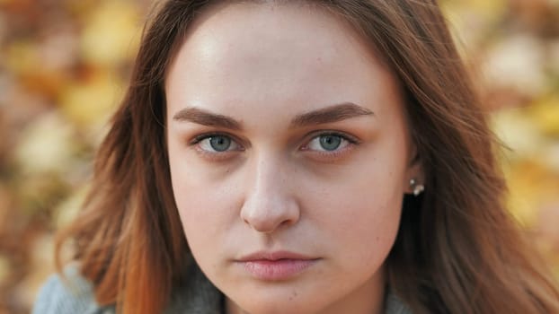 Portrait of a young and beautiful girl against a background of yellow leaves. Face close up
