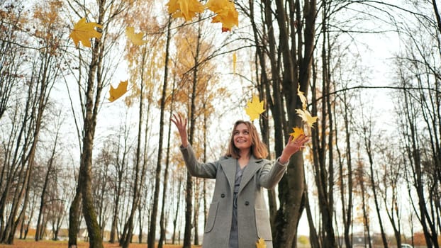 A young girl throws up leaves in an autumn park
