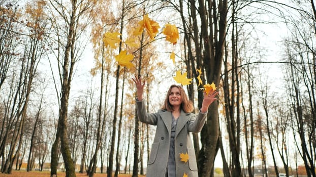 A young girl throws up leaves in an autumn park