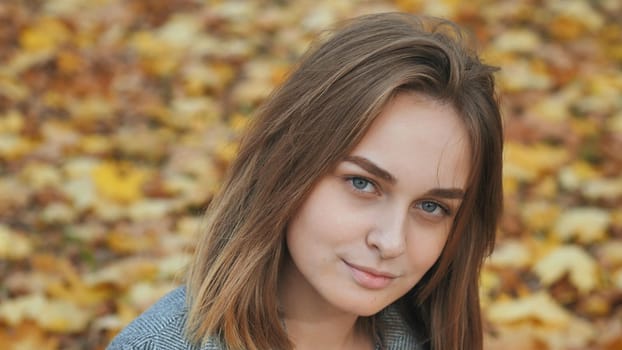 Portrait of a young and beautiful girl against a background of yellow leaves. Face close up