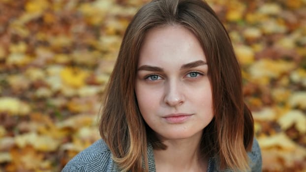 Portrait of a young and beautiful girl against a background of yellow leaves. Face close up