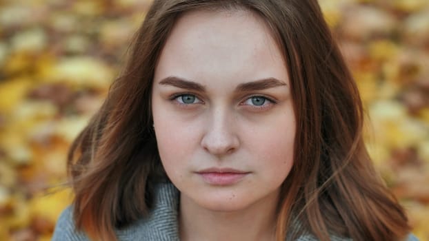 Portrait of a young and beautiful girl against a background of yellow leaves. Face close up