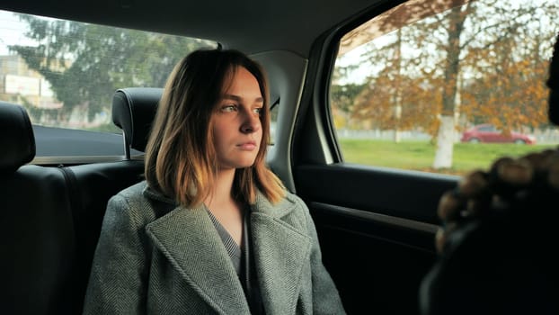 A sad young girl drives in a car salon in the fall