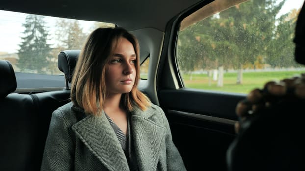 A sad young girl drives in a car salon in the fall