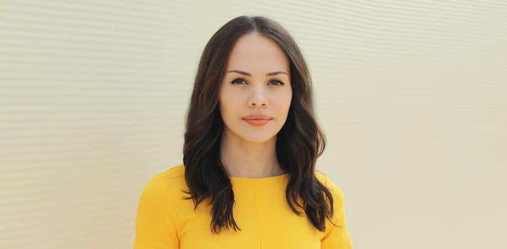 Portrait of beautiful young brunette woman looking at camera against wall background