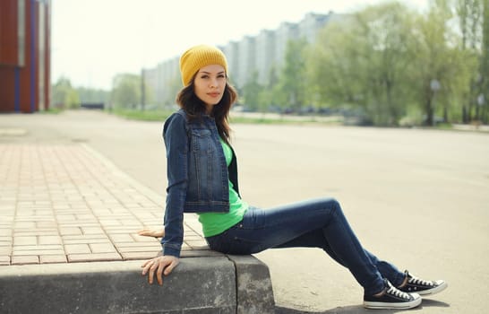 Beautiful brunette young woman in hat, jacket posing on city street