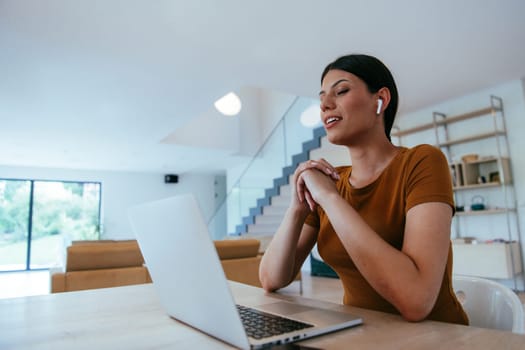 Woman sitting in living room using laptop looking at cam talk by video call with business friend relatives, head shot. Job interview answering questions