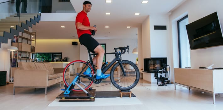 A triathlete riding a triathlon bike on a machine simulation in a modern living room.
