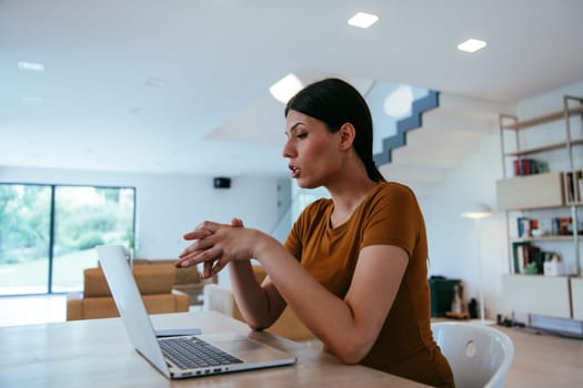 A woman sitting in the living room using a laptop and a smartphone look at camtalk by video call with business friends and relatives, head shot. Job interview answering questions
